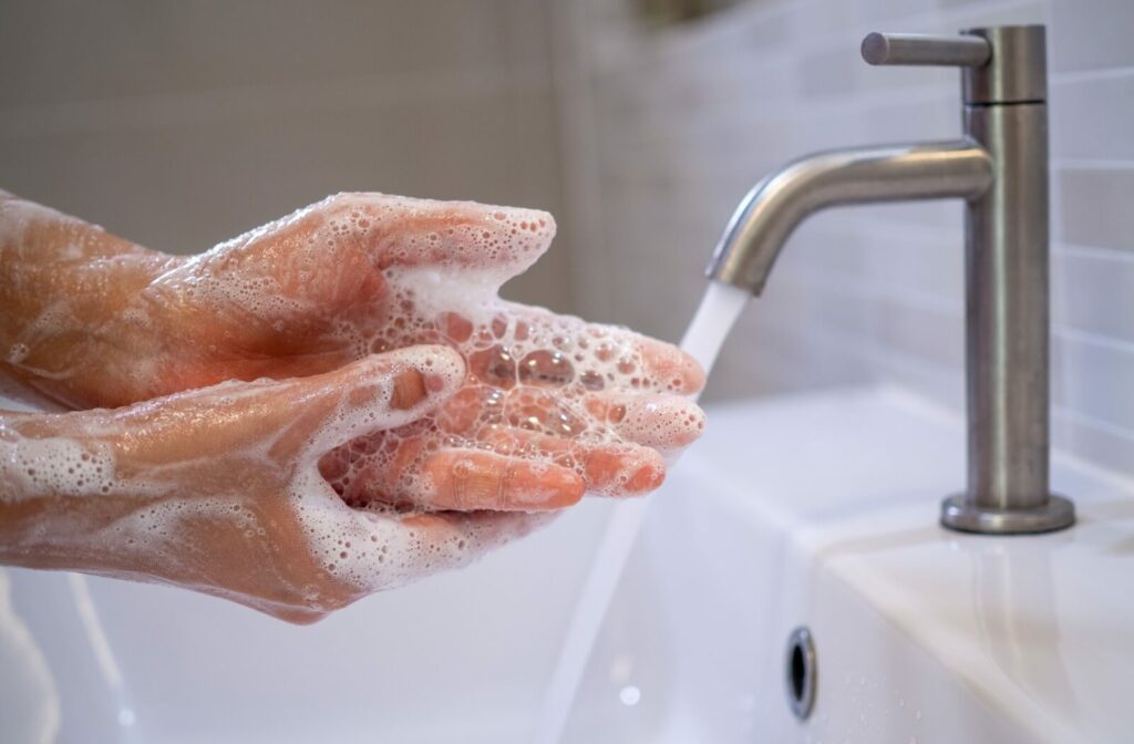 Someone washes their hands with warm water and soap before they put their contact lenses into their eyes.