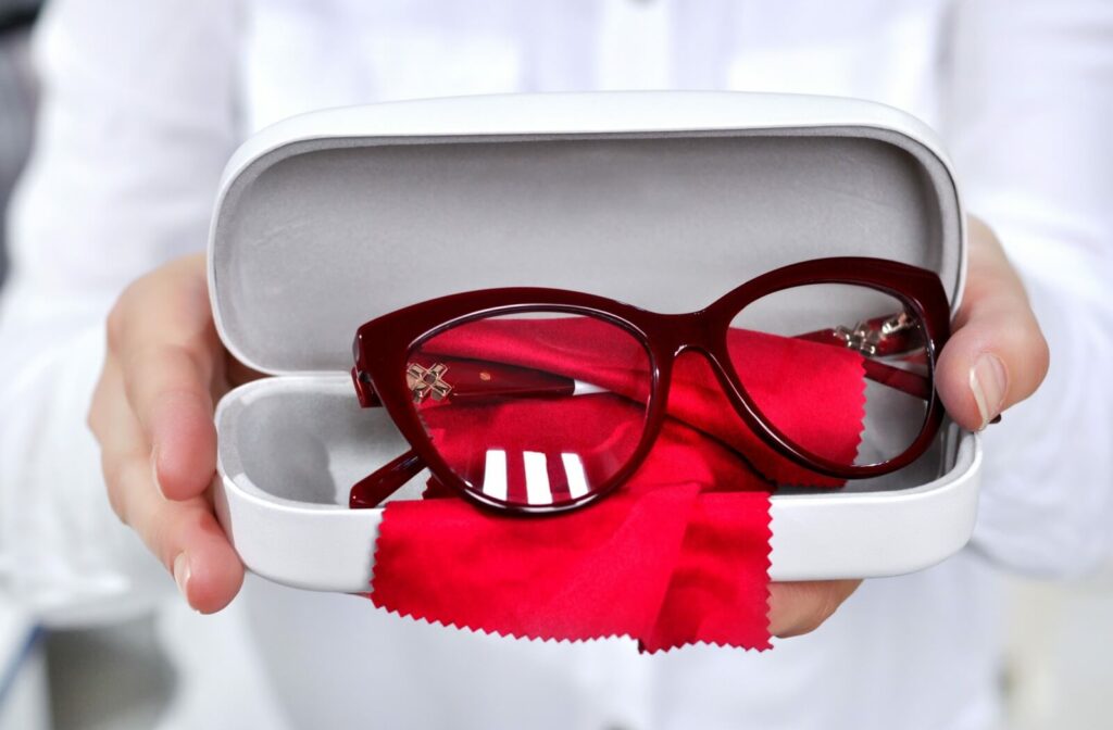 An optometrist holds a new pair of eyeglasses that are placed in their case.