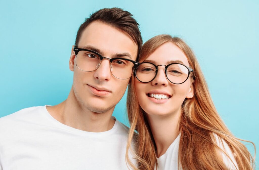 A young smiling couple poses while wearing fashionable glasses.