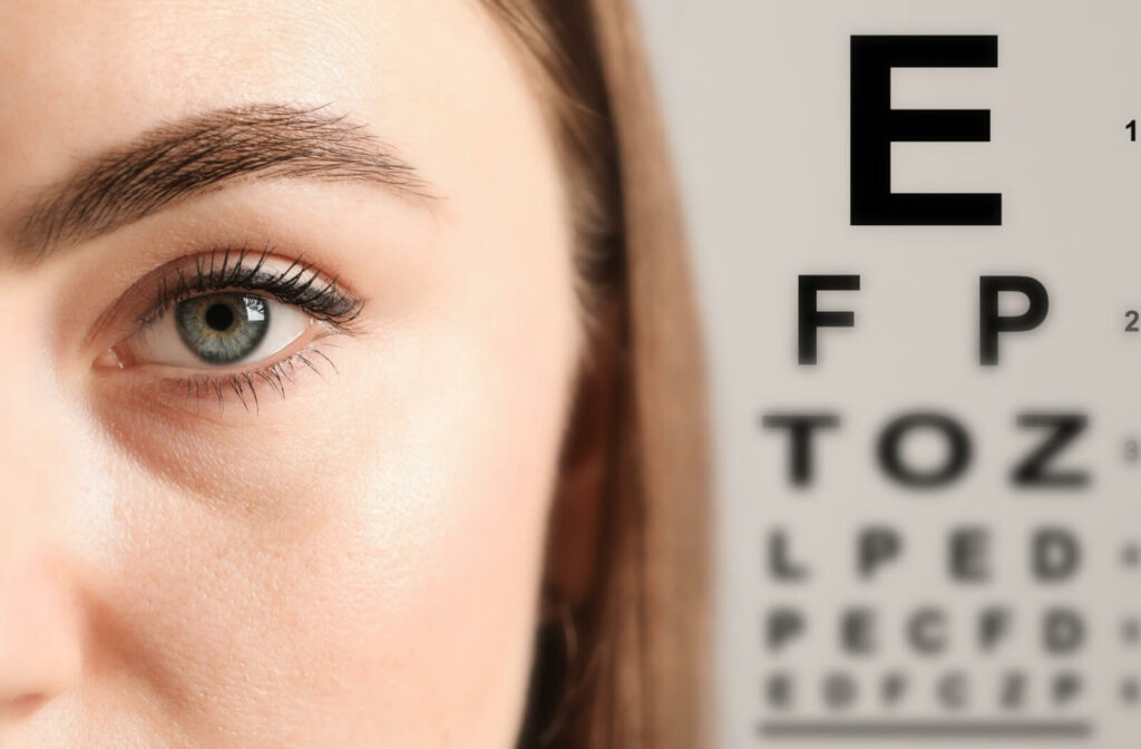Close-up of an eye with a Snellen eye chart in the background, representing vision testing during an eye exam.